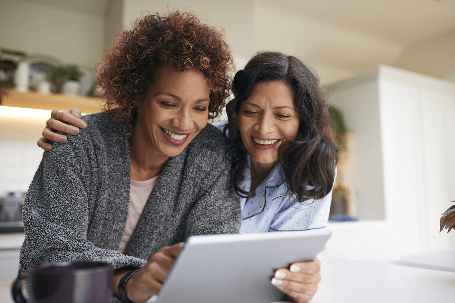 Two women looking at a tablet and smiling